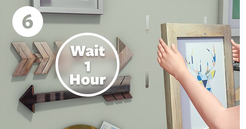 Step 6 of how to use picture hooks - wait 1 hour for adhesive to build. Align strips and press frame

