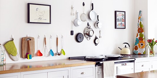 kitchen wall corner decoration ideas by hanging pots, pans, and spatulas on the wall.