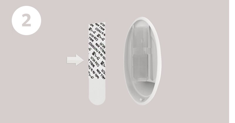 Step 2 of wall hook installation: separate strips, remove red liner and press adhesive to hook
